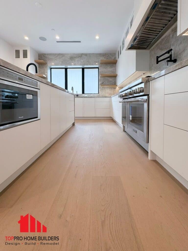 Modern kitchen with white cabinets, marble countertops, and built-in appliances.