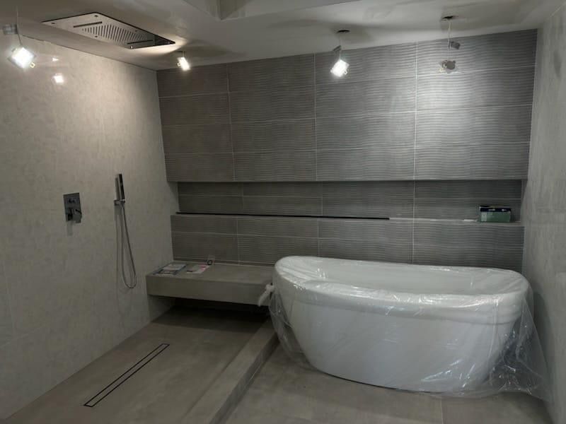 Bathroom with freestanding tub, grey tiles, and rain showerhead.