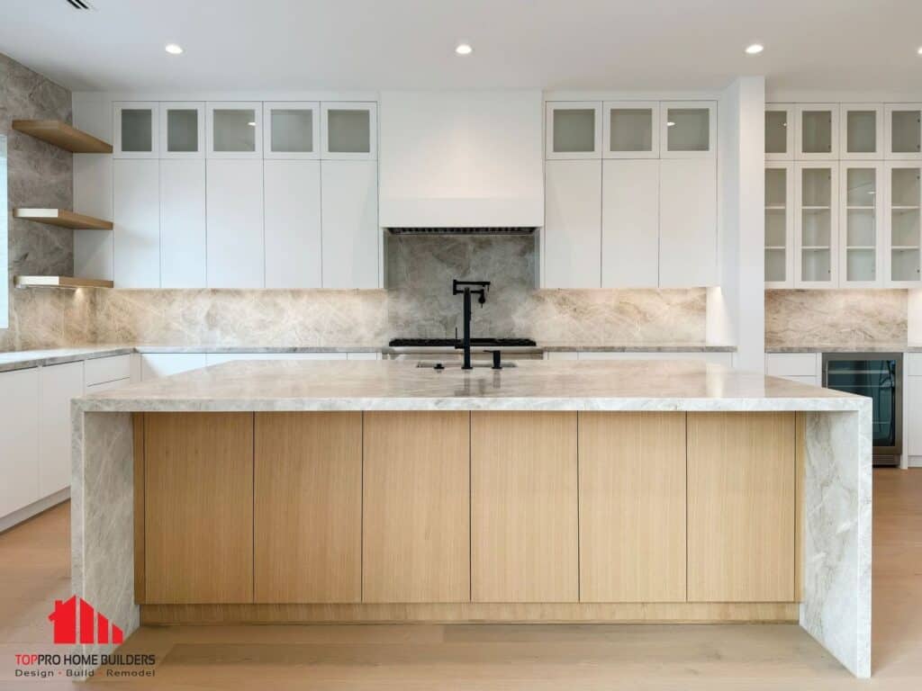 Image of a modern kitchen with a marble island and white cabinets.