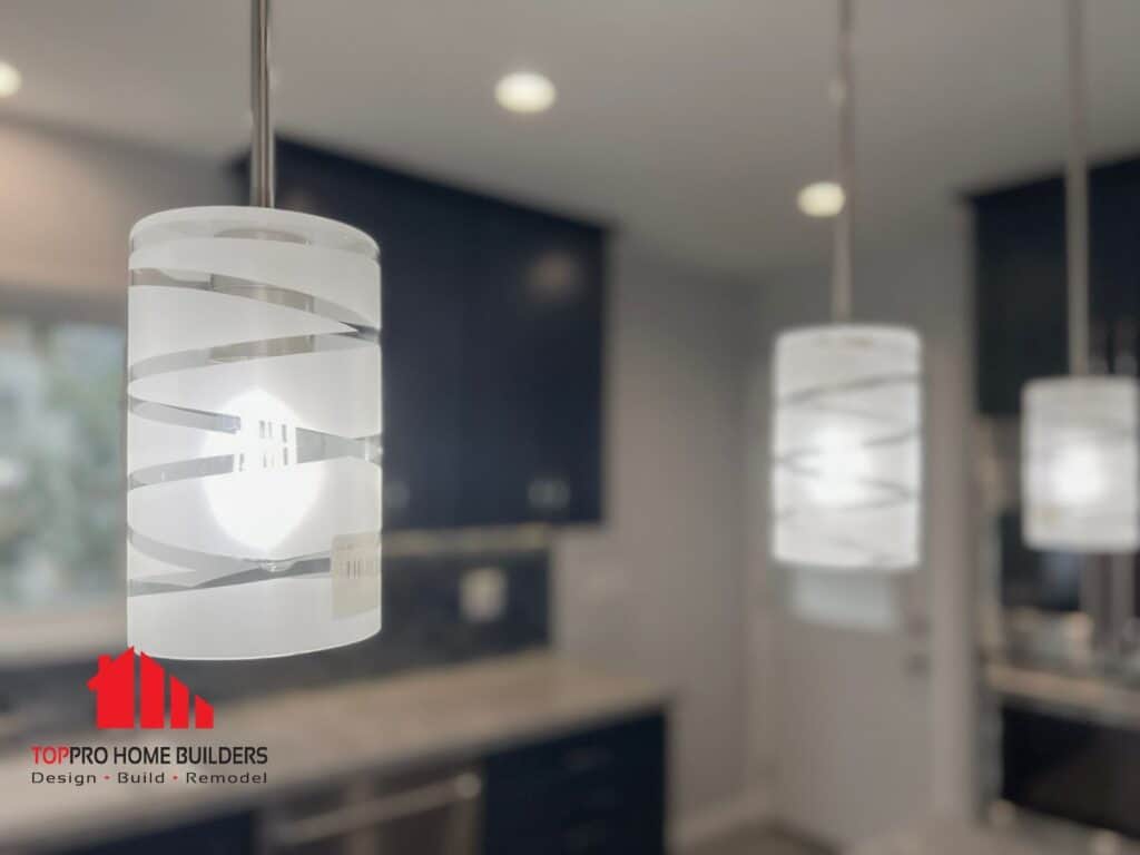 Close-up of modern pendant lights in a remodeled kitchen with Top Pro Home Builders logo.