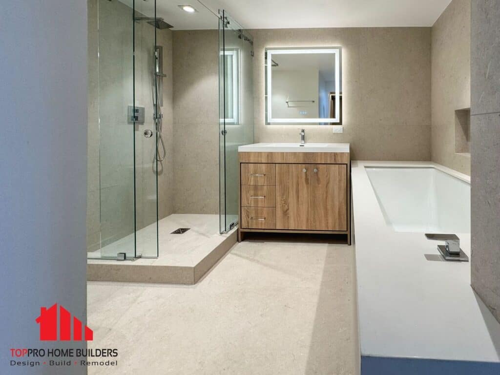 Image of a modern bathroom with glass shower, wooden vanity, and bathtub.