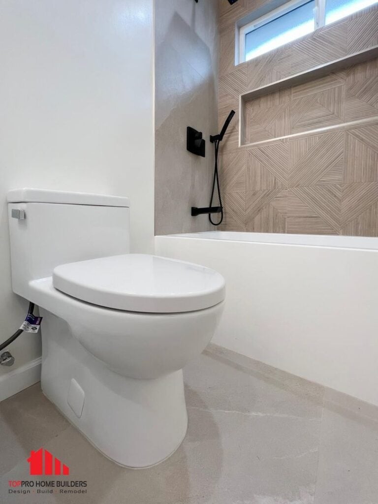 Image of a modern bathroom with a white toilet and geometric tile design in the shower area.