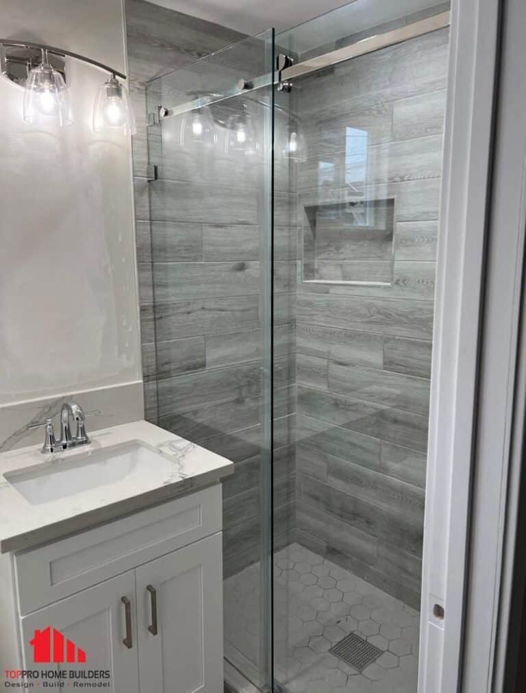 Image of a modern bathroom with glass shower enclosure and white vanity.