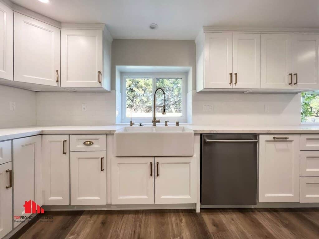 Image of a modern kitchen with white cabinets, farmhouse sink, and stainless steel dishwasher.