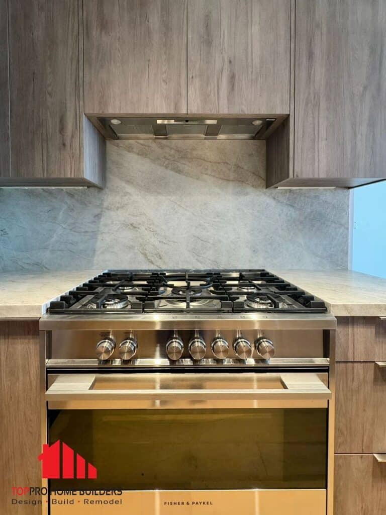 Kitchen featuring a stainless steel Fisher & Paykel gas stove, wooden cabinets, and a stone backsplash.