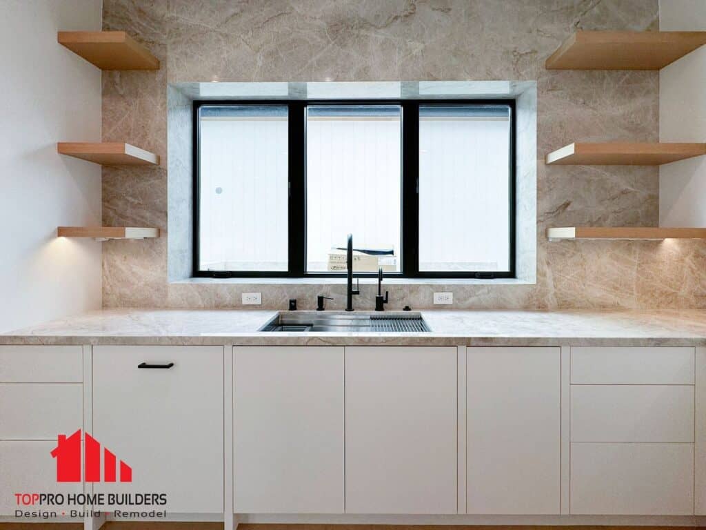 Modern kitchen with marble backsplash, open shelves, and stainless steel sink.