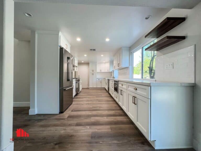 Image of a modern kitchen with white cabinets, stainless steel appliances, and wooden flooring.