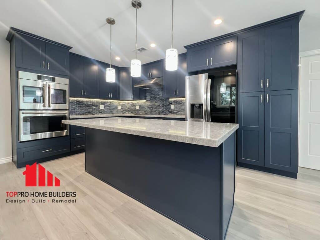 Modern kitchen with dark blue cabinets, stainless steel appliances, and a central island.