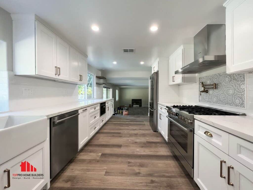 Image of a modern kitchen with white cabinets, stainless steel appliances, and hardwood flooring.