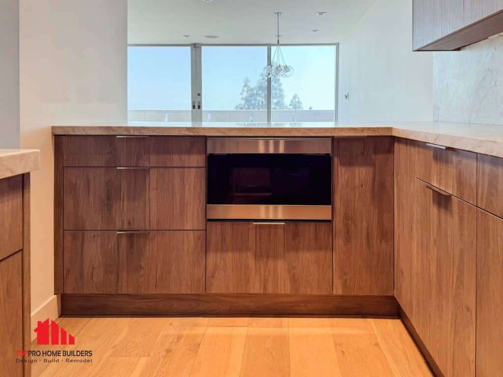 Image of a modern kitchen with wooden cabinets and built-in microwave under natural lighting.