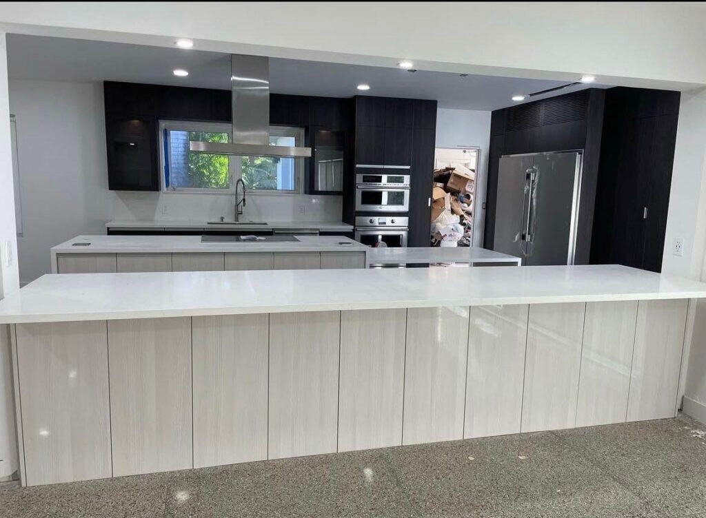 Image of a modern kitchen with stainless steel appliances and a large white island.