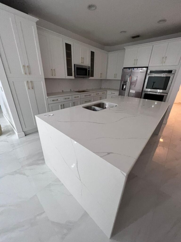 Image of a modern kitchen with a marble island and built-in appliances.