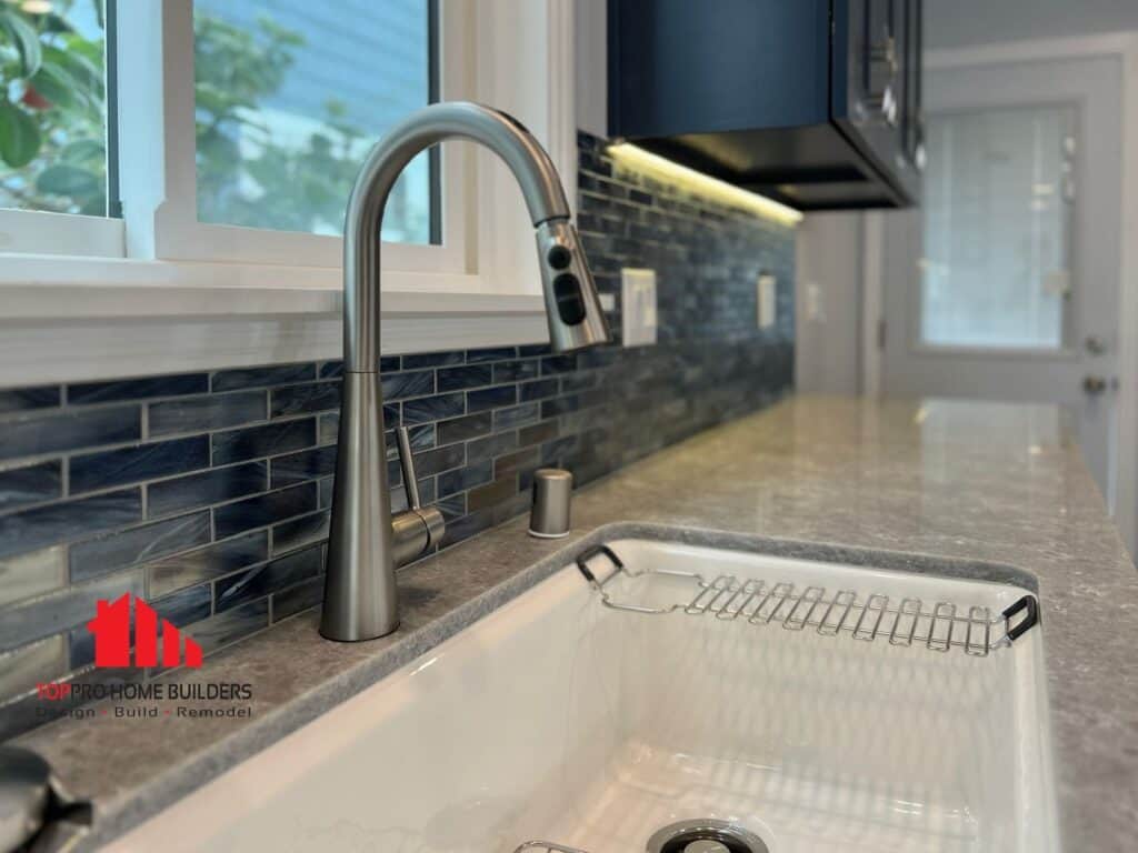 Modern kitchen sink with stainless steel faucet and blue tile backsplash.