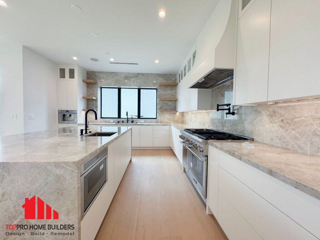 Modern kitchen with white cabinets, marble countertops, and built-in appliances.