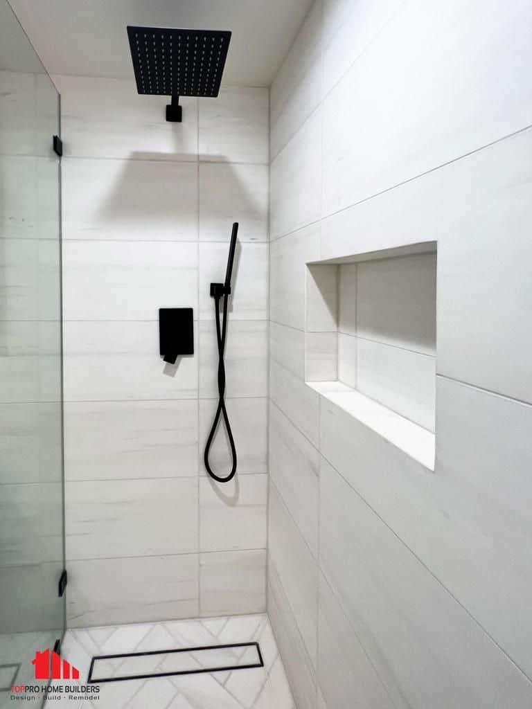 Image of a modern shower area with white tiles and black fixtures.