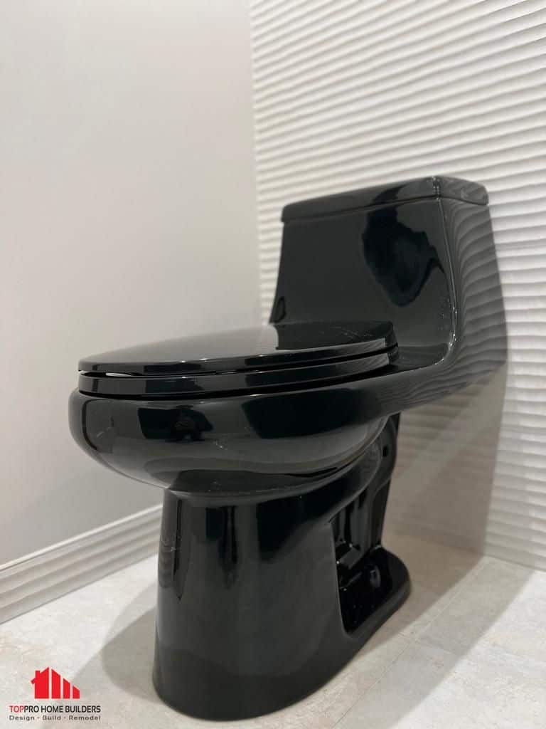 Black toilet installed in modern bathroom with textured white wall.