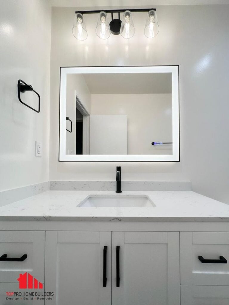 Bathroom vanity with white countertop, black faucet, and LED-lit mirror.