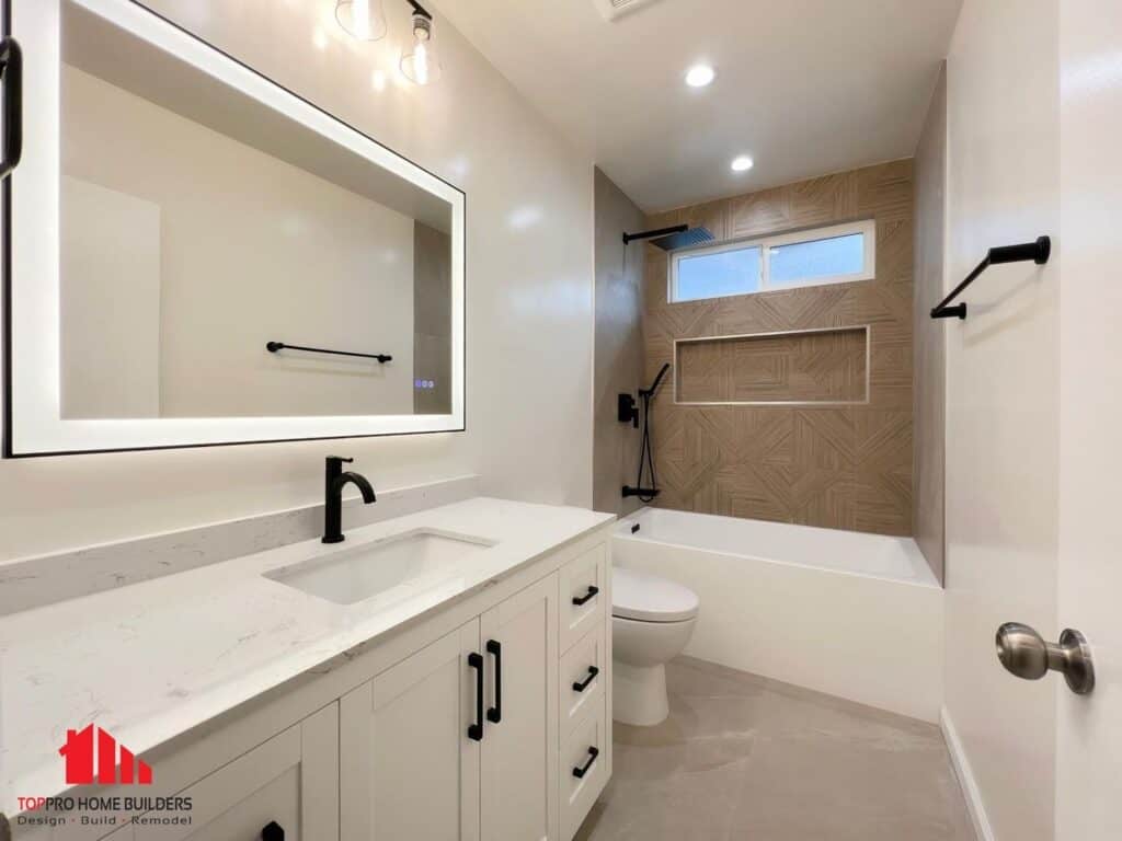 Bathroom with modern vanity, illuminated mirror, and geometric tile bathtub surround.