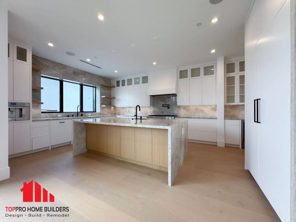 Image of a modern kitchen with a marble island, white cabinets, and built-in appliances.