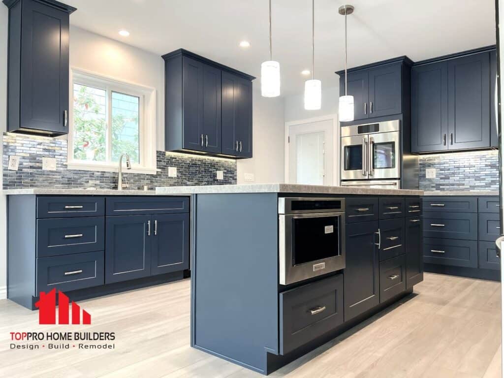 Image of a modern kitchen with navy cabinets, stainless steel appliances, and pendant lighting.