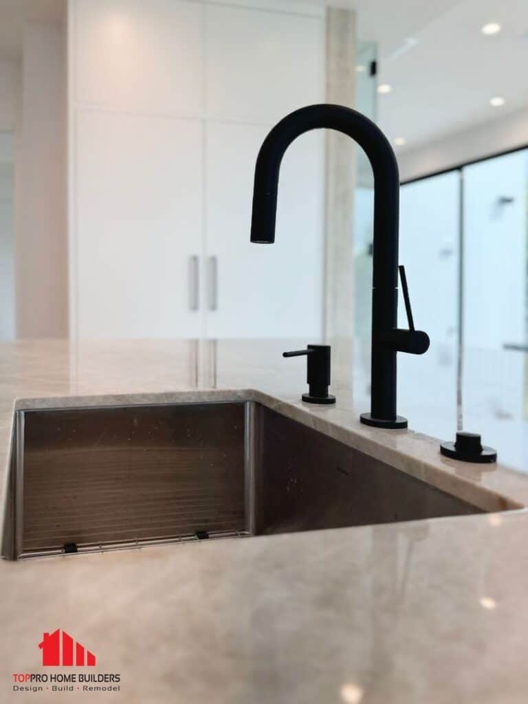 Modern kitchen sink with matte black faucet and light stone countertop.