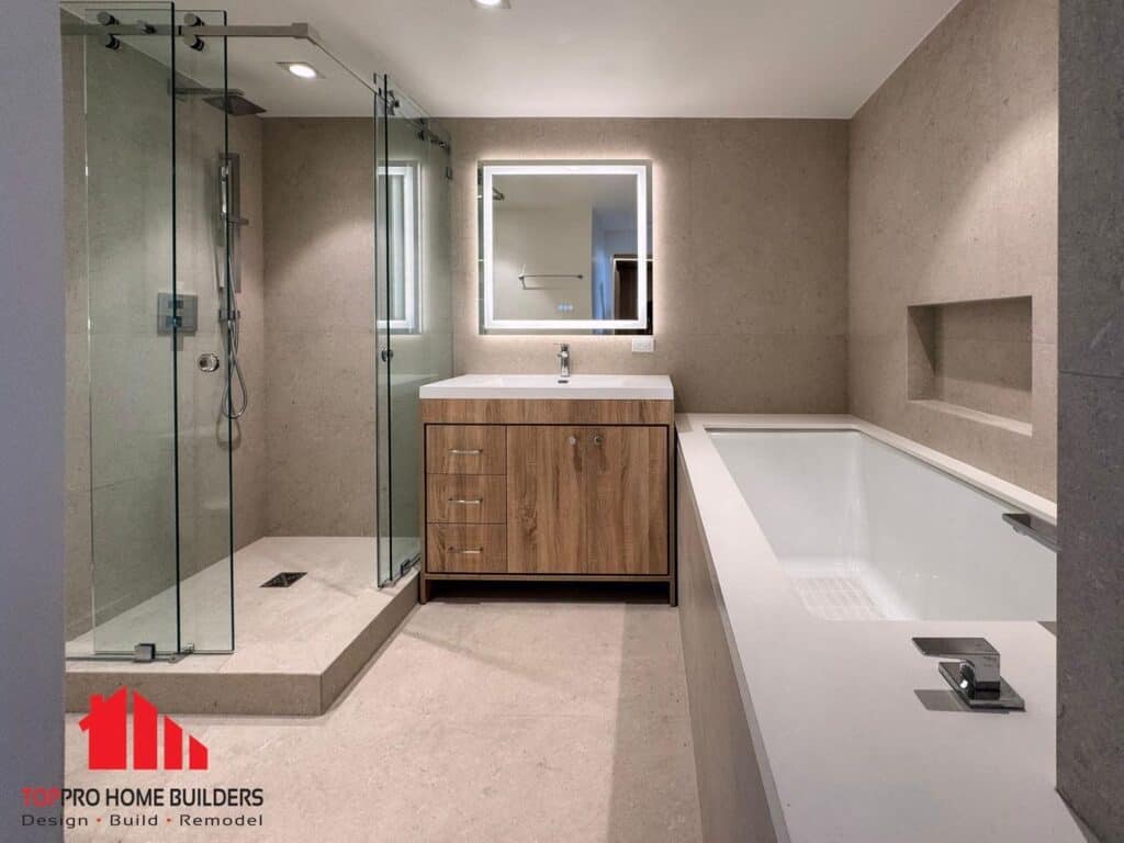 Image of a modern bathroom with glass shower, wooden vanity, and bathtub.