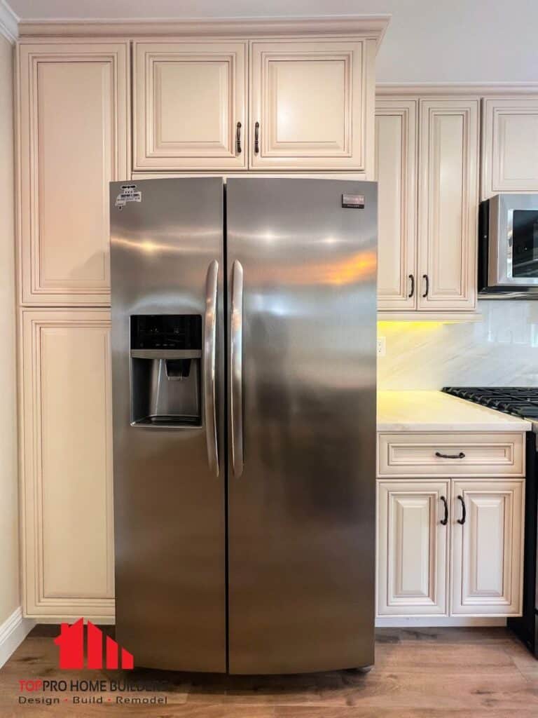 Kitchen with stainless steel refrigerator and cream cabinets.