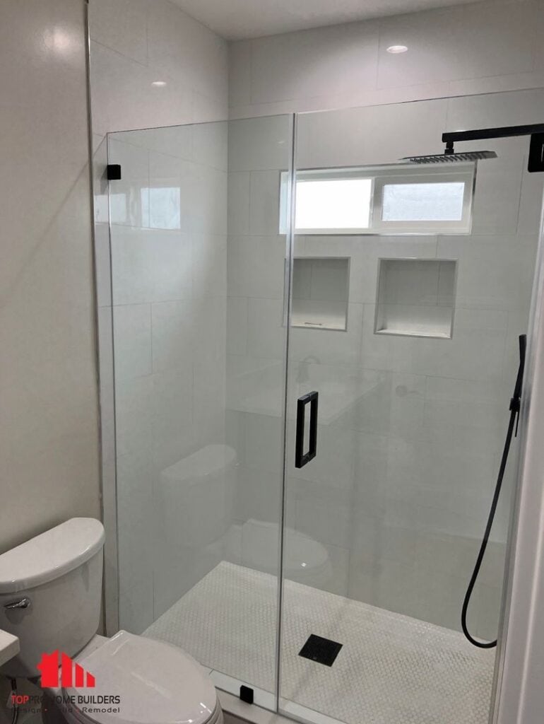 Image of a modern bathroom with a glass-enclosed shower and white tiles.