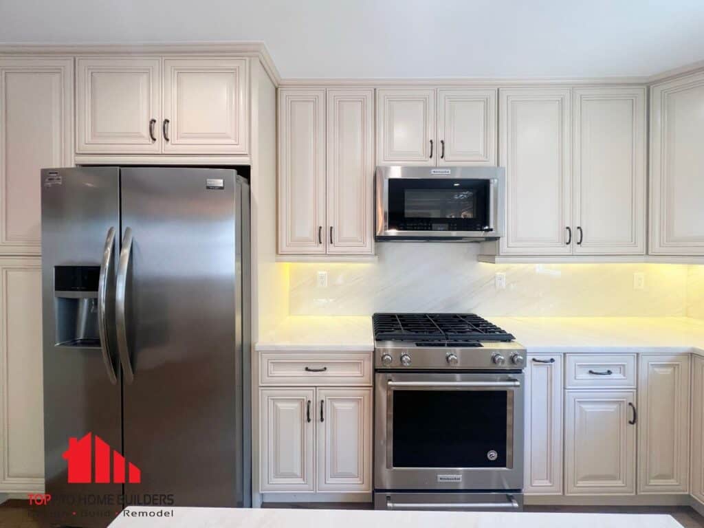 Kitchen with stainless steel fridge, gas range, microwave, and cream cabinets.